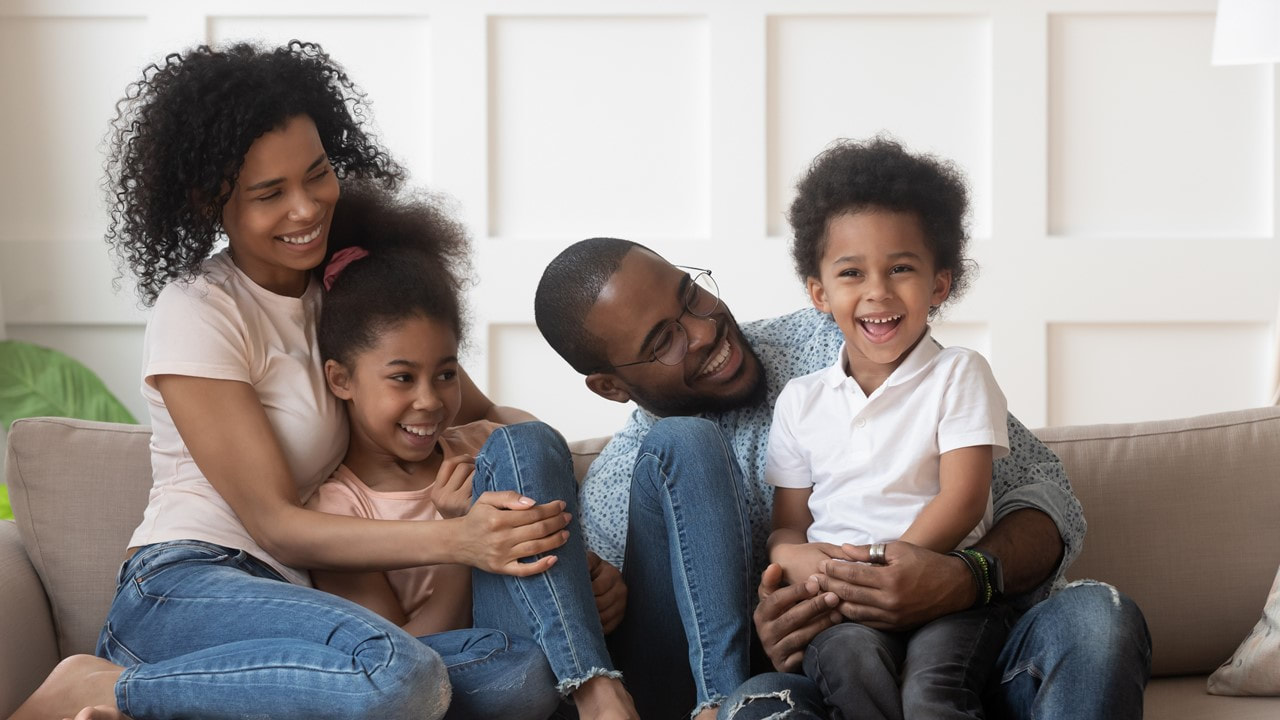 Young parents on a sofa with their two your children - Life Insurance - Lake Charles La - Kelly Lee Insurance
