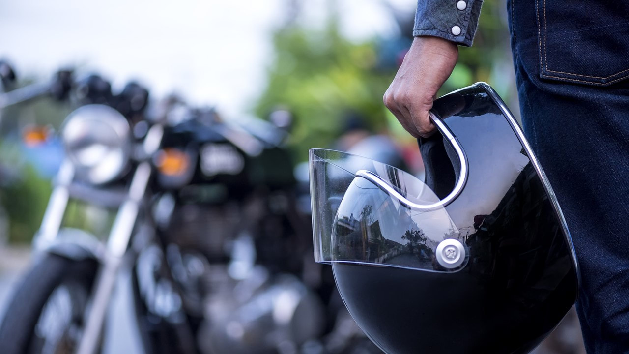 Image of a guy holding a black helmet in front of a blurred out motorcycle - Motorcycle Insurance Lake Charles La - Kelly Lee Insurance